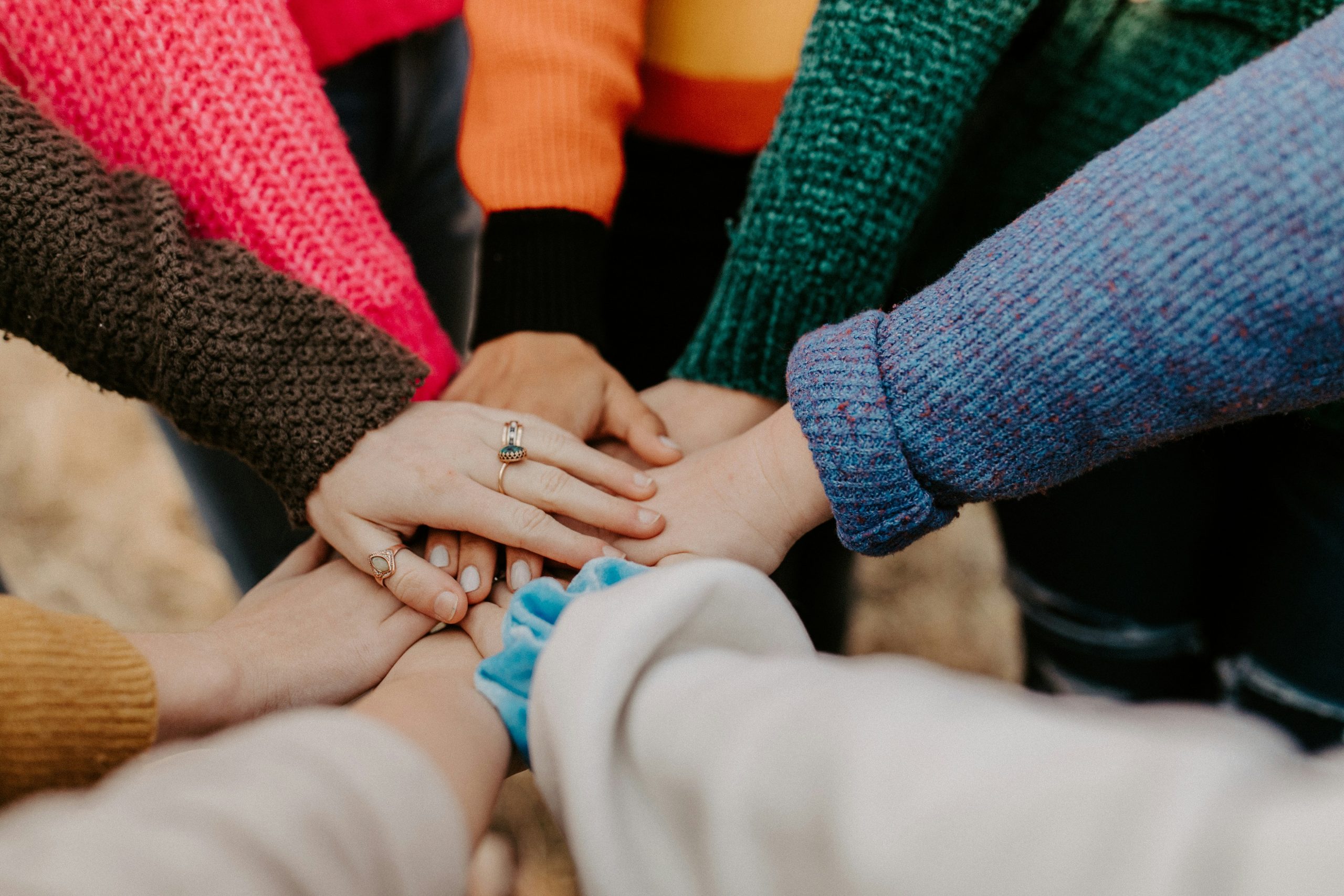 Close-up of multiple hands stacked together, symbolizing teamwork and unity.